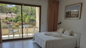 Une chambre à coucher avec un lit, une petite table et un balcon avec des chaises.