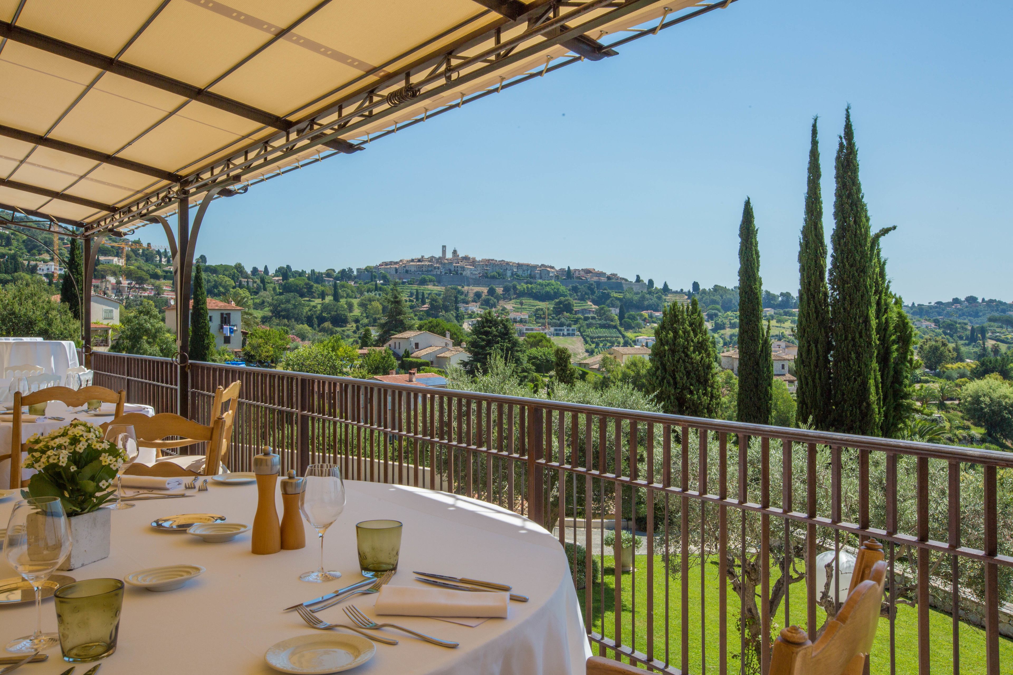 A table set for dining with a view of a hillside town.