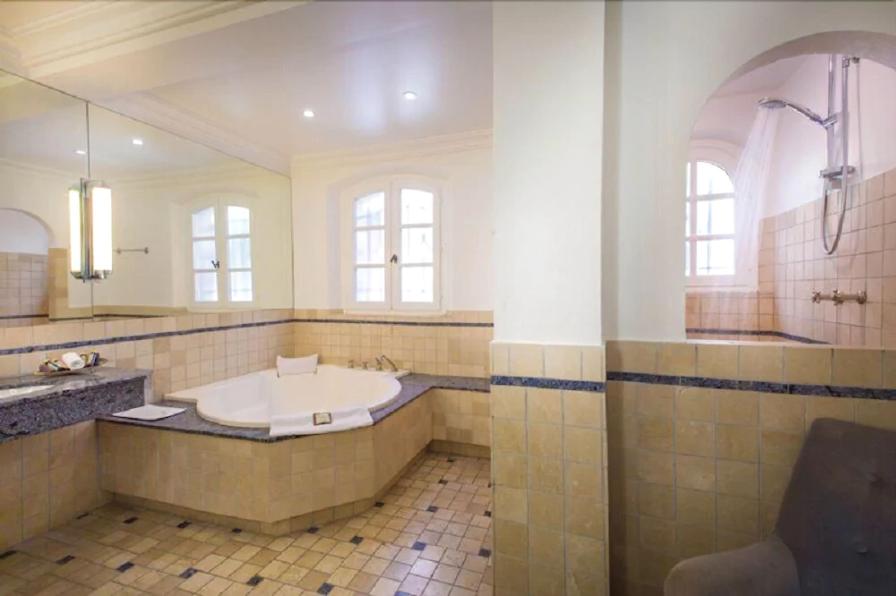 A spacious bathroom with a large bathtub, a separate shower area, and a vanity with a mirror.
