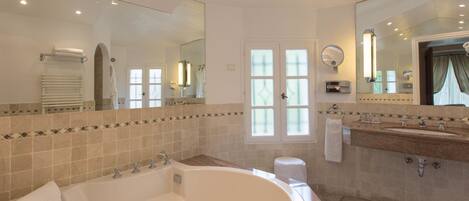 Un baño moderno con una bañera grande, un lavabo y un espejo.