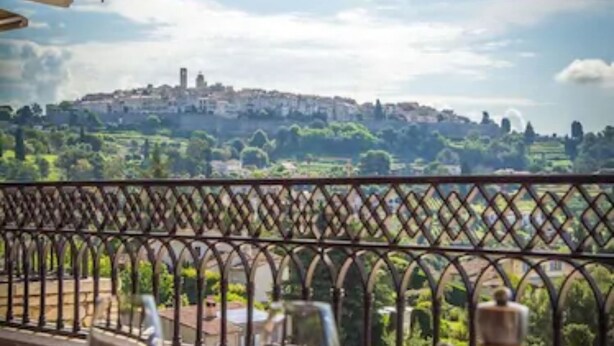 A table set for dining with a view of a distant town and greenery.