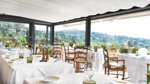 An outdoor dining area with tables set for a meal, overlooking a scenic landscape.