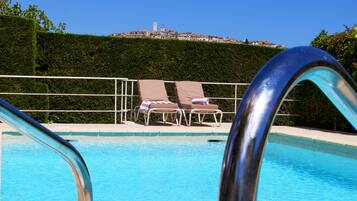 A swimming pool with two lounge chairs and a metal pool ladder.