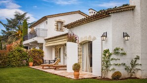 A two-story house with a patio, outdoor seating, and a garden.