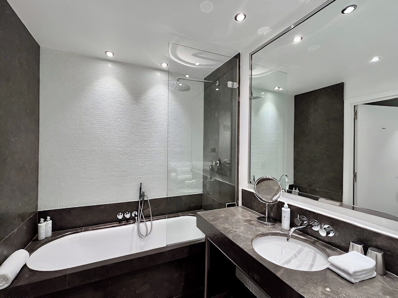 A modern bathroom with two sinks, a large mirror, and a shower.