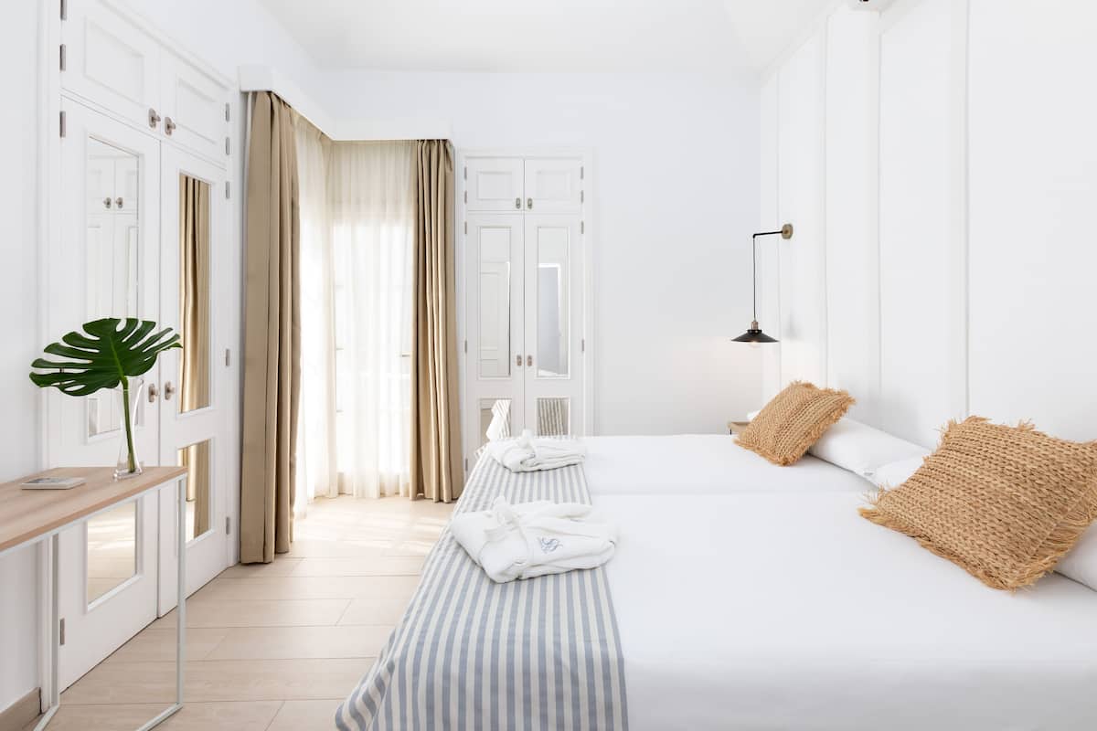 A hotel room with a bed, bedside table, and a mirror.