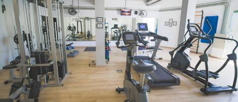 A gym with various exercise equipment including treadmills, elliptical machines, and weight machines.