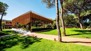 Un bâtiment moderne doté d’une façade en bois et de grandes fenêtres en verre, entouré de pelouses et d’arbres bien entretenus.