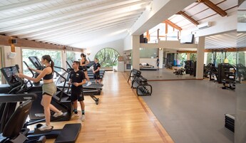 Un gimnasio con cintas de correr, pesas y un muro de espejos.