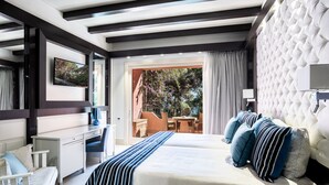 A hotel room with a bed, a desk, a chair, a telephone, and a view of the outdoors. - Forte Village Resort - Il Castello (Pula)