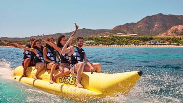A group of people on a yellow inflatable raft in a body of water with a mountainous backdrop.