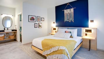 A modern bedroom with a bed, bedside tables, a wall-mounted macrame piece, framed pictures, and a mirror.