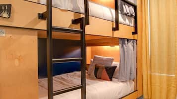 Une chambre avec un lit superposé, une tête de lit en bois, une échelle et un rideau.