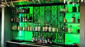 A bar area with shelves of liquor bottles and glasses. - The Monterey Motel (Albuquerque)