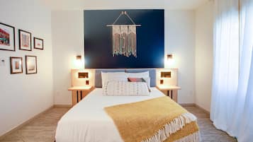 Un cuarto de hotel ordenado con una cama grande, lámparas de noche, una obra de arte montada en la pared y cuadros enmarcados.