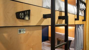 Una cama tipo litera con cabecera de madera y un letrero que indica el número de habitación 204.