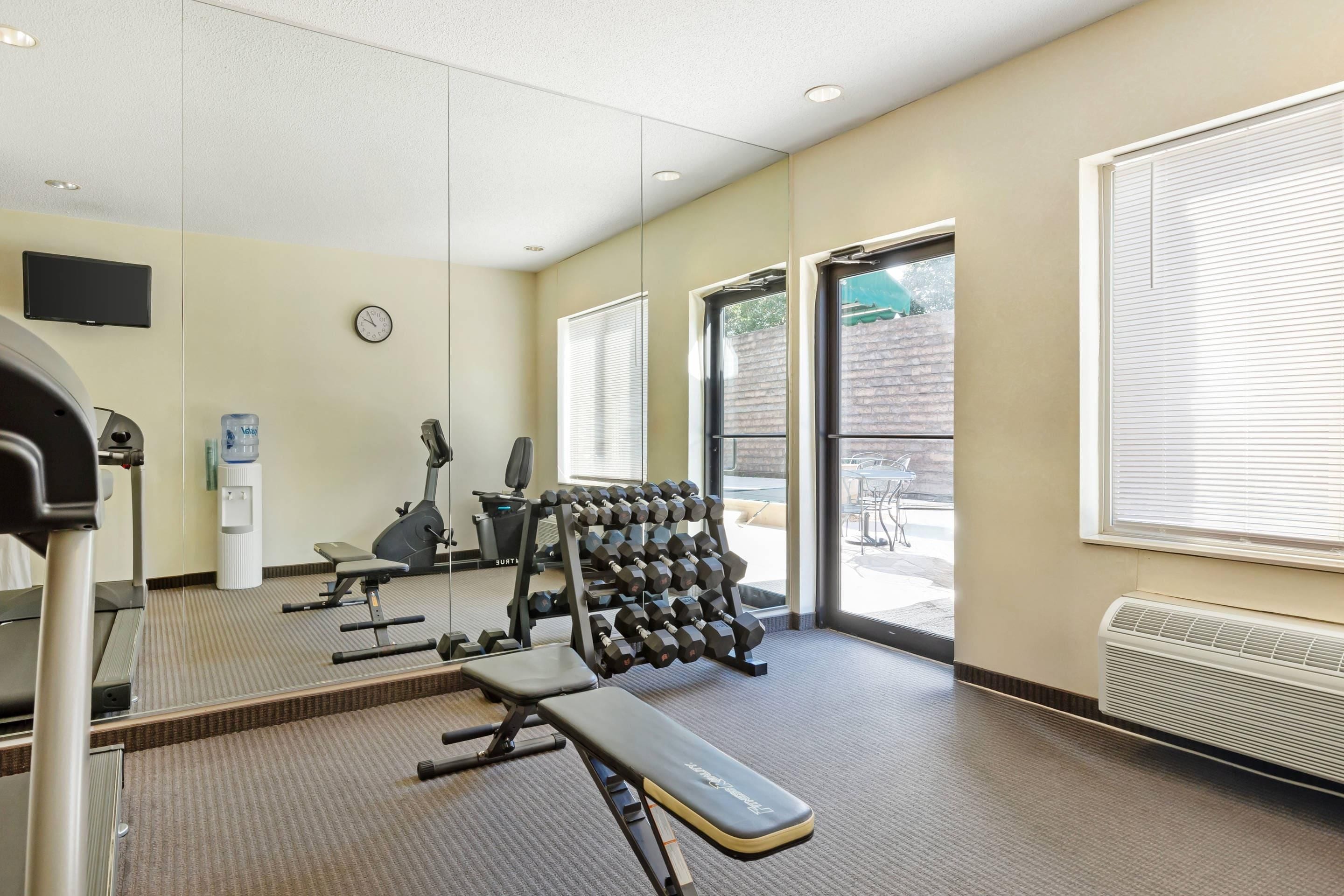A gym with exercise equipment, a water dispenser, and a clock on the wall.