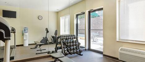 A gym with exercise equipment, a water dispenser, and a clock on the wall.