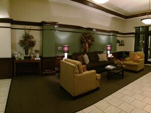 A lobby with a sofa, armchairs, a coffee table, and a reception desk with a vase of flowers. - Sleep Inn & Suites Danville Hwy 58 (Danville)