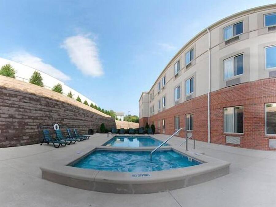 A swimming pool area with lounge chairs and a brick wall.