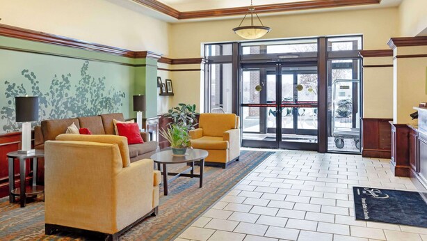 A lobby with a sofa, armchairs, a coffee table, a lamp, and a potted plant.