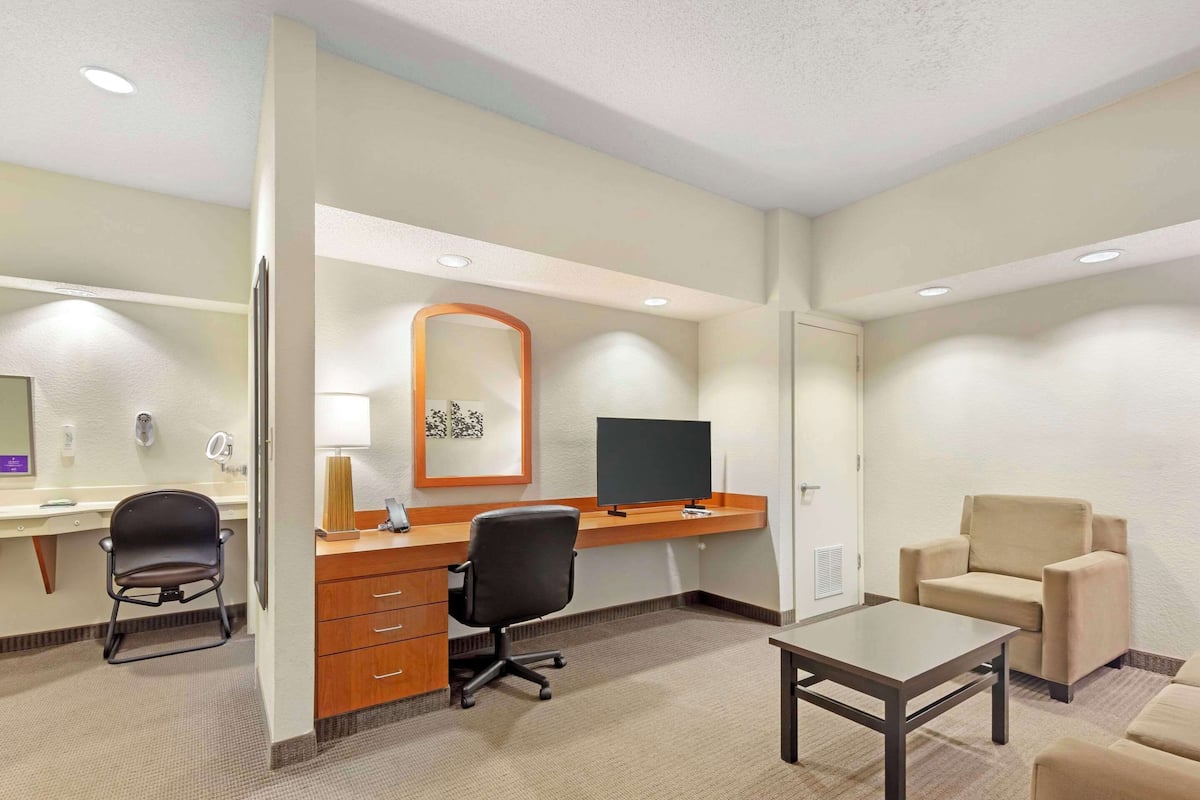 Een hotelkamer met een bureau, stoel, bank en een televisie.