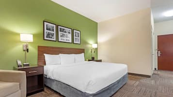 A hotel room with a bed, two bedside tables, a chair, and a door.