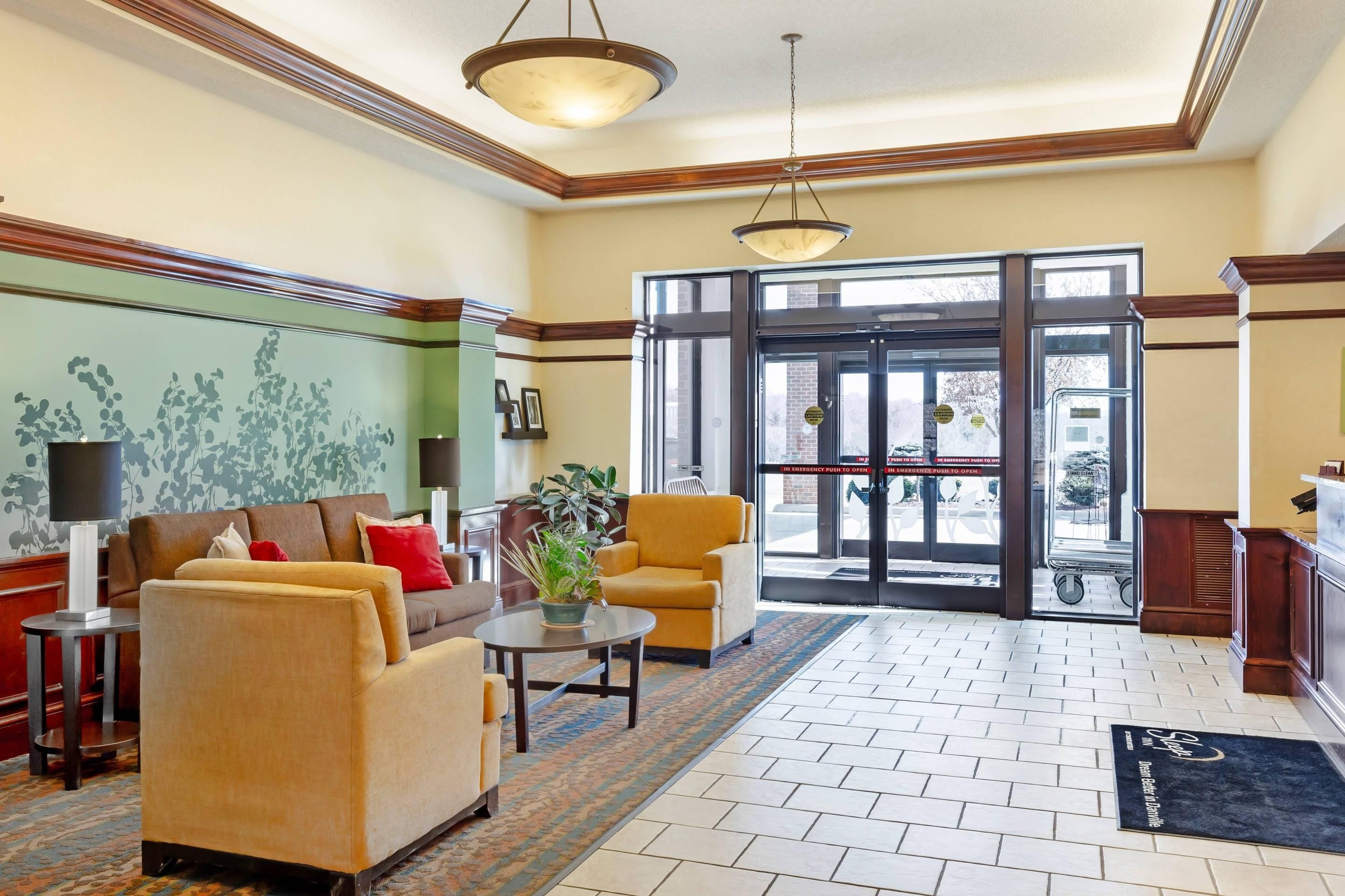 A lobby with a sofa, armchairs, a table, and a potted plant.