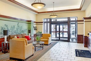 A lobby with a sofa, armchairs, a table, and a potted plant.