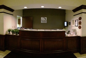 A reception area with a wooden reception desk, a sign for 'Sleep Inns & Suites', a television, and framed certificates on the wall. - Sleep Inn & Suites Danville Hwy 58 (Danville)