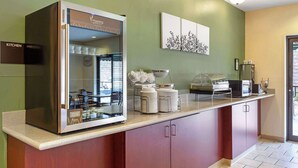 A kitchen area with a refrigerator, a coffee station, and a wall-mounted artwork.