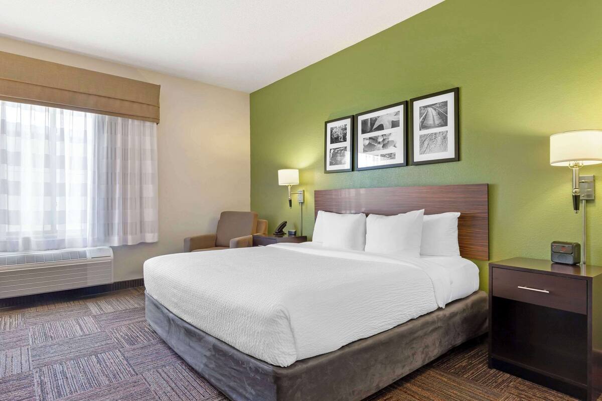 Een hotelkamer met een groot bed, een bureau, een stoel, een lamp en een wandradiator.