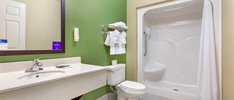 Ein Badezimmer mit grüner Wand, Waschbecken in Weiß, Toilette und Badewanne in Weiß.