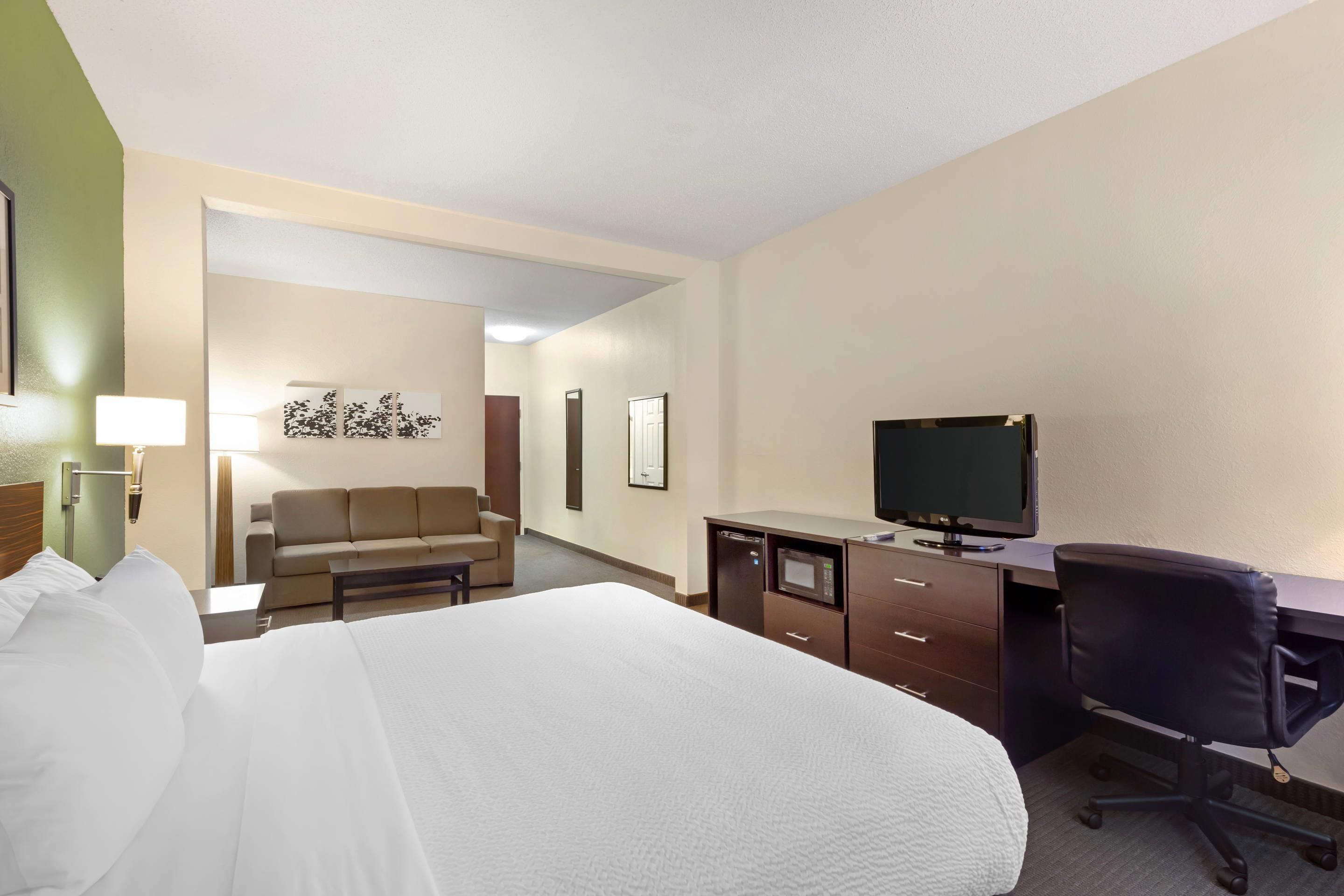 Habitación de hotel con cama, escritorio con computadora, una silla, televisor y sofá.