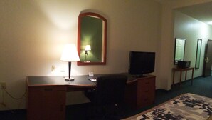 Een hotelkamer met een bed, een bureau met een lamp, een televisie en een spiegel.