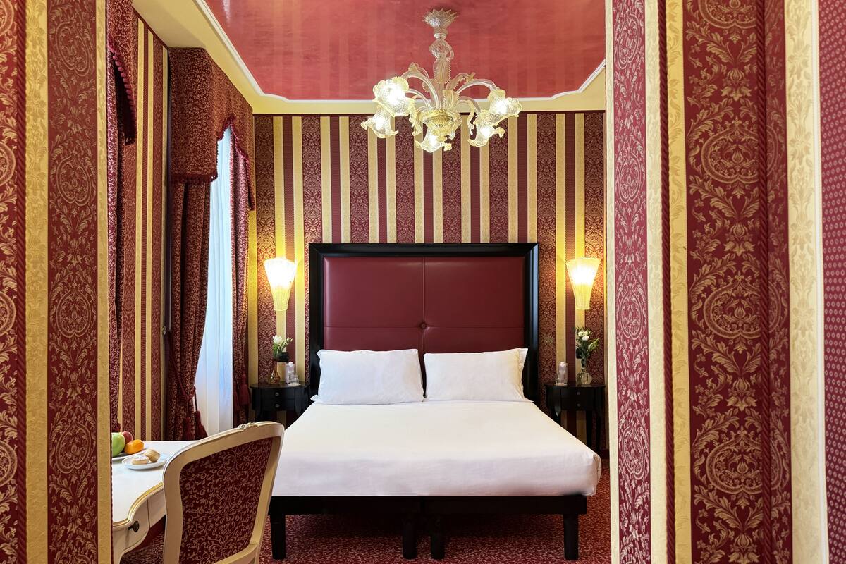 Una habitación de hotel con una cama grande, un escritorio con silla y un candelabro.