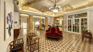 Un lobby espacioso con techo ornamentado, un sofá de terciopelo rojo y un suelo a cuadros.