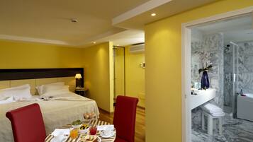 Ein Hotelzimmer mit Bett, Frühstückstisch und einem Badezimmer mit Dusche und Marmorwänden.