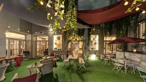 Un patio interior con césped artificial, mobiliario de mimbre y plantas colgantes.