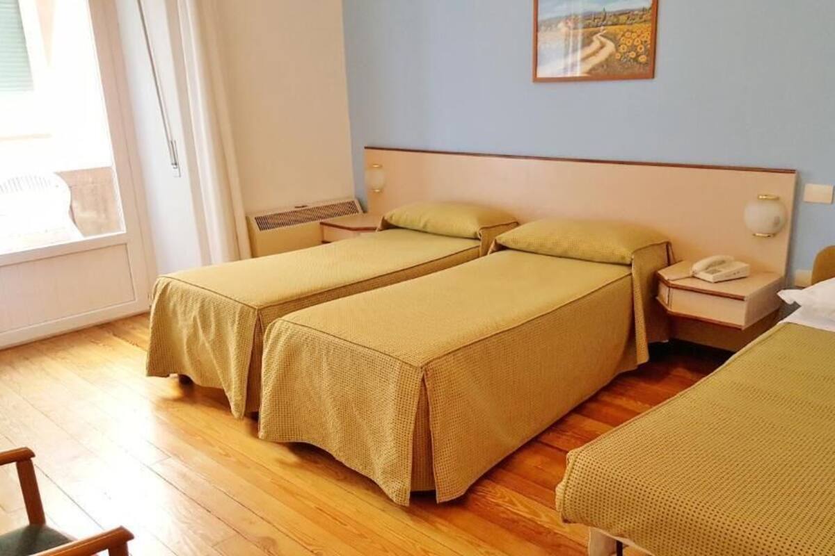 Une chambre avec deux lits simples, une table de chevet avec une lampe, un téléphone et un tableau au mur.