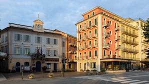 A hotel with a balcony, a clock tower, and a sign indicating it is a hotel. - Hotel Italie Et Suisse (Stresa)
