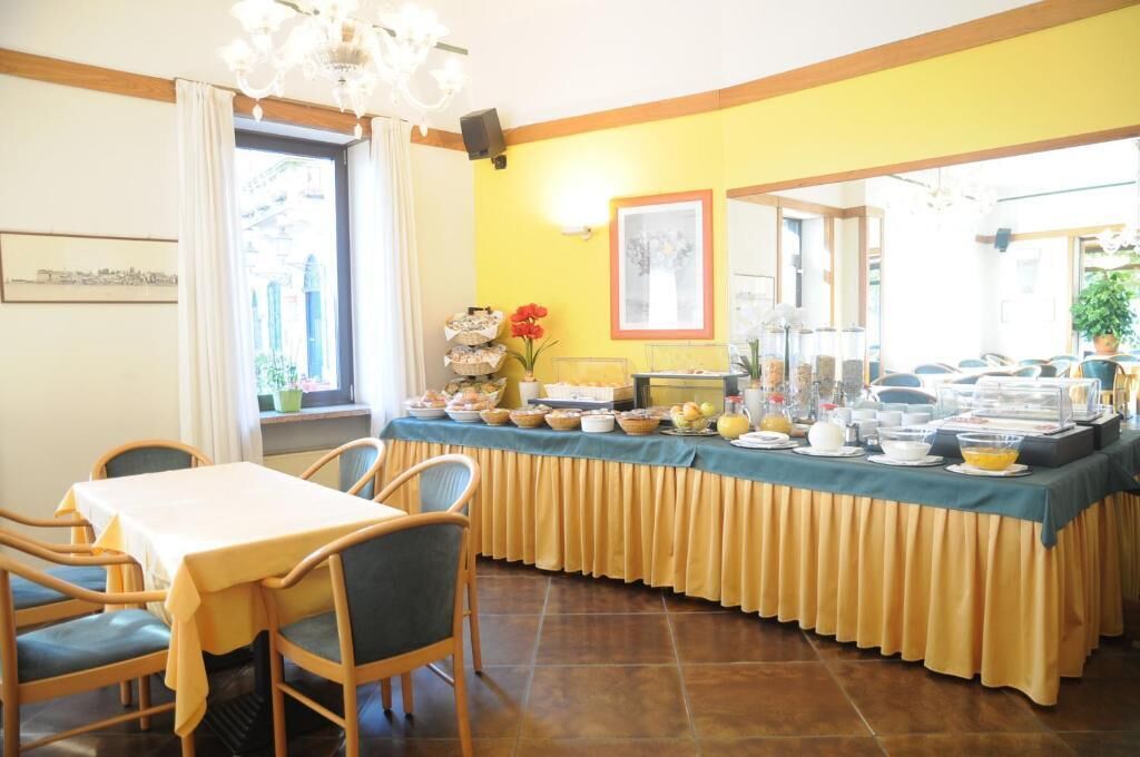 A breakfast buffet with various food items and a seating area with chairs and a table.
