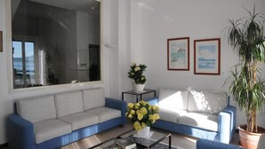 A living room with a grey sofa, a blue sofa, a coffee table, and a large window. - Hotel Italie Et Suisse (Stresa)