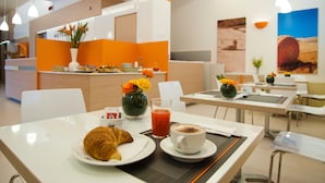 A modern dining area with tables, chairs, and a central counter with a flower vase and a painting. - Hotel Rodia (Maglie)