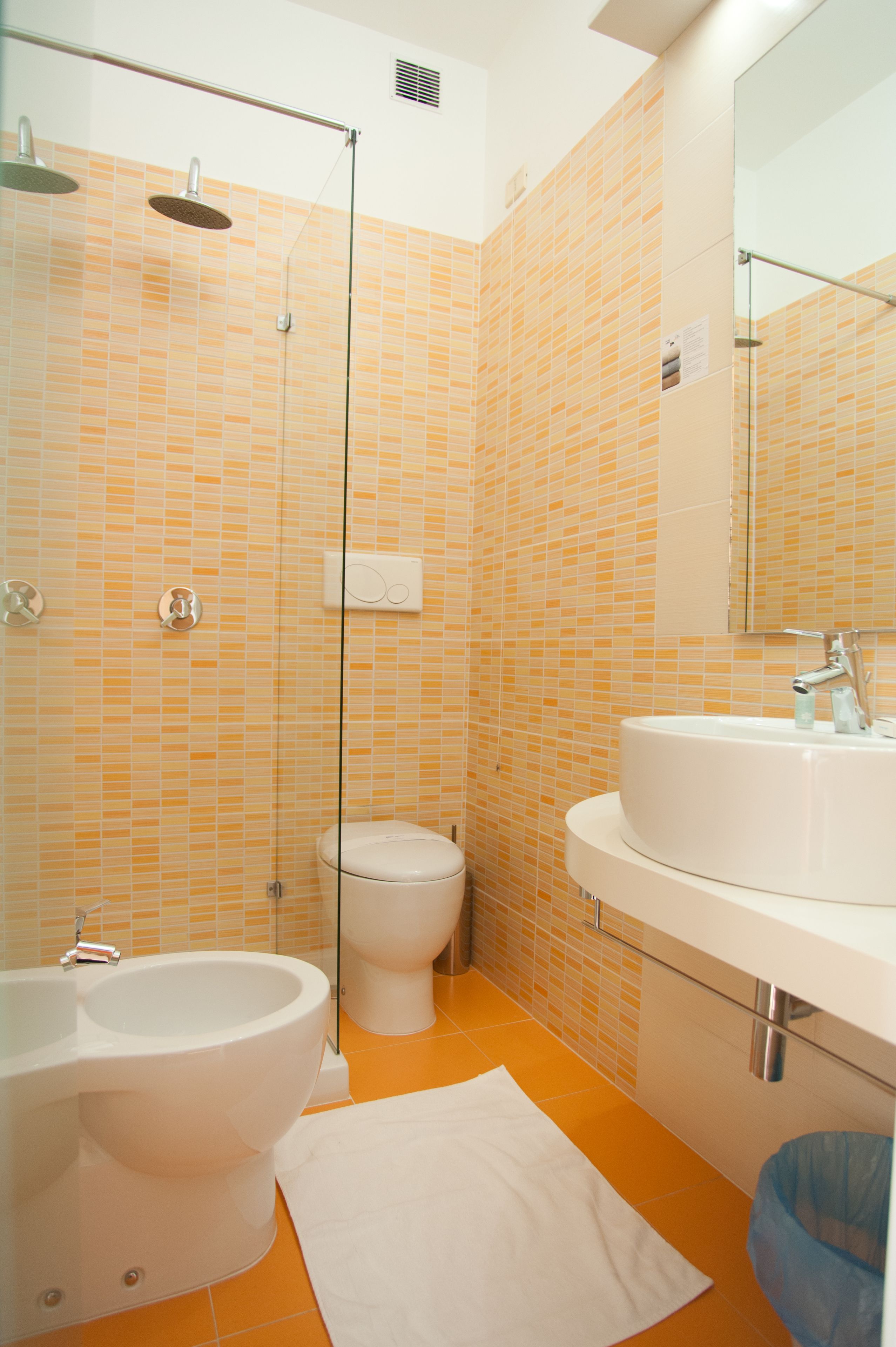 A bathroom with a shower, toilet, bidet, and sink.
