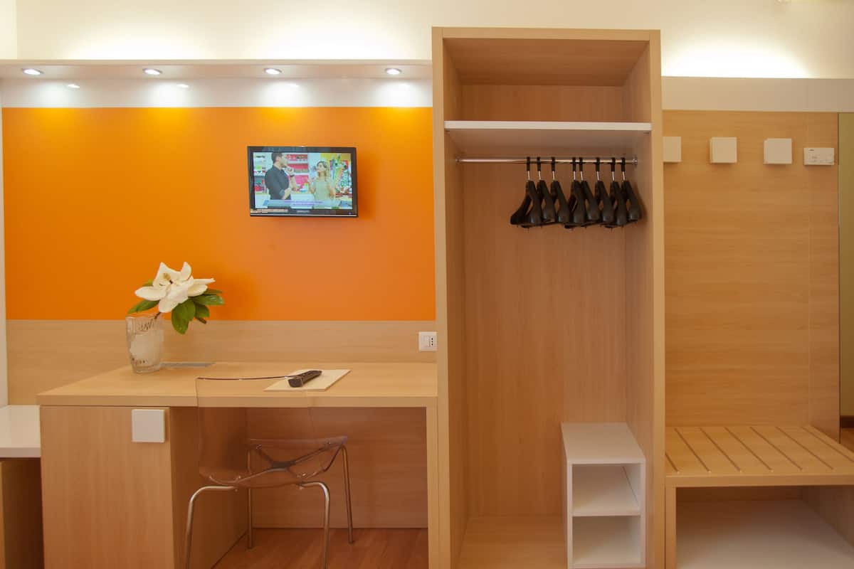 A hotel reception area with a wooden counter, a television mounted on the wall, and a shoe rack.