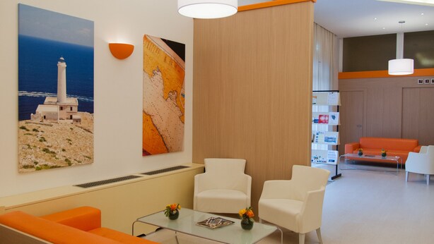 A modern hotel lobby with a seating area, a coffee table, and artwork on the walls. - Hotel Rodia (Maglie)