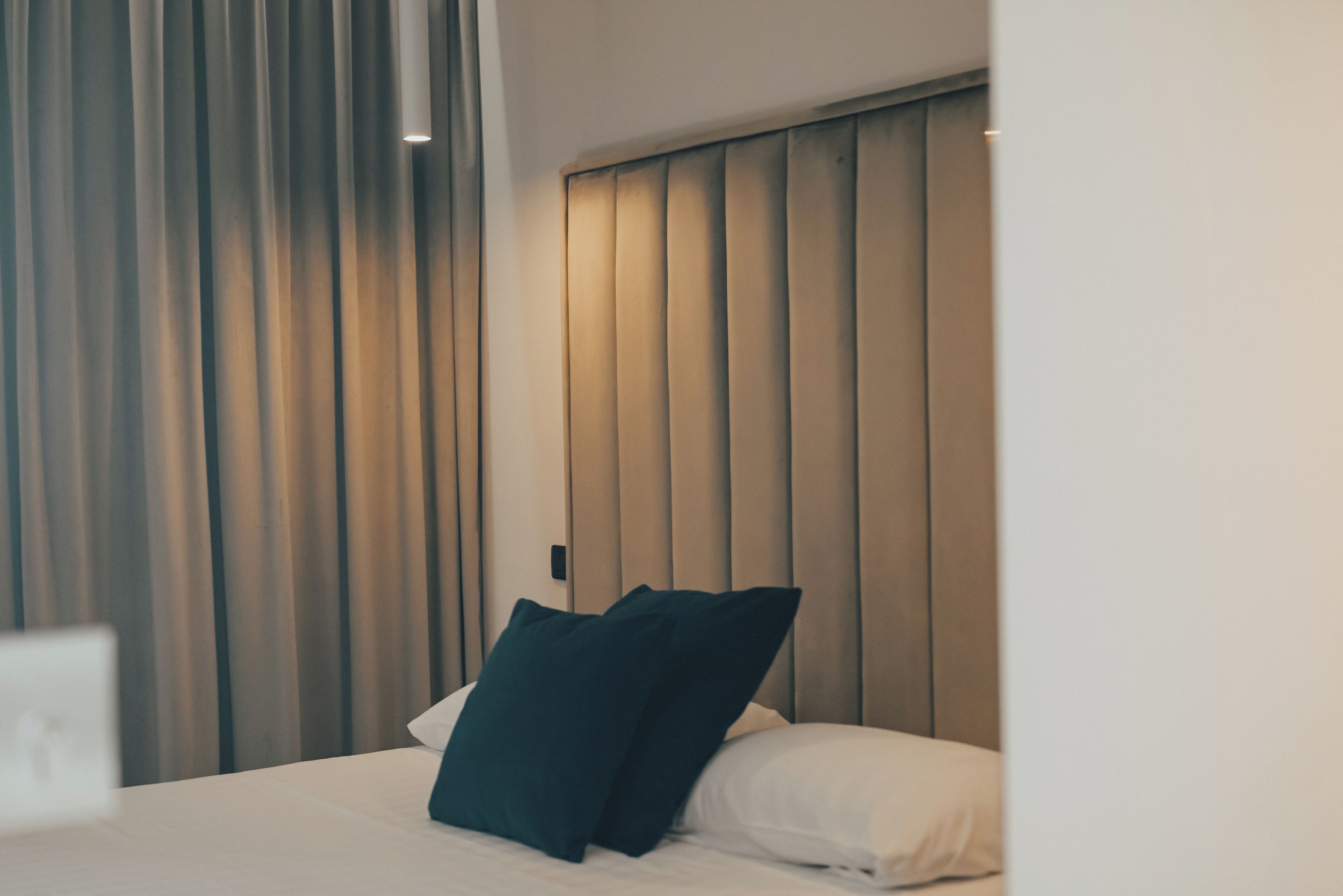 Une chambre d’hôtel avec un lit, une tête de lit et un rideau.