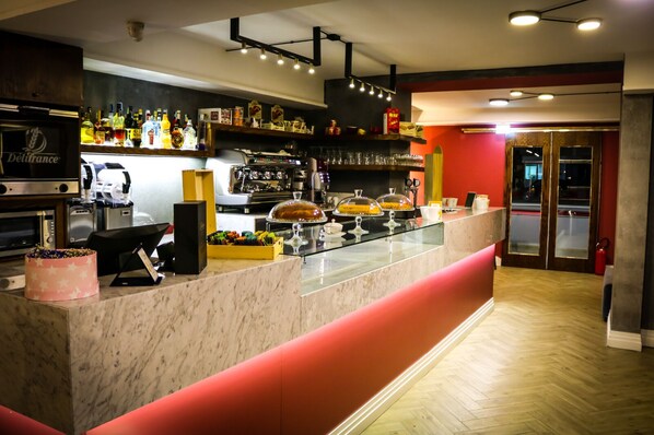 A bar area with a marble counter, shelves with bottles, a coffee machine, and a glass display case. - Puteoli Palace Hotel (Pozzuoli)