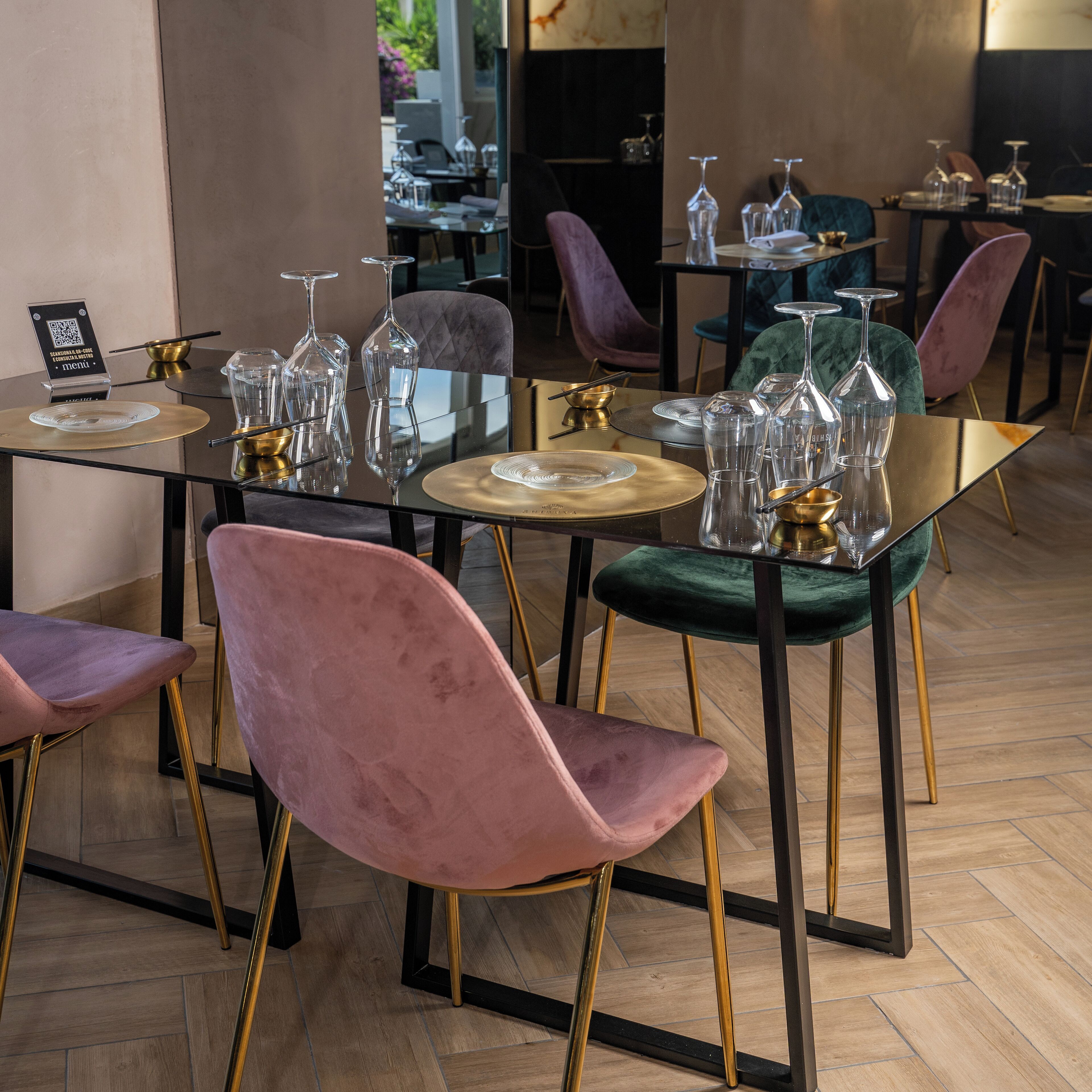 Een eetgedeelte met een glazen tafel, gouden accenten en fluweelzachte stoelen.